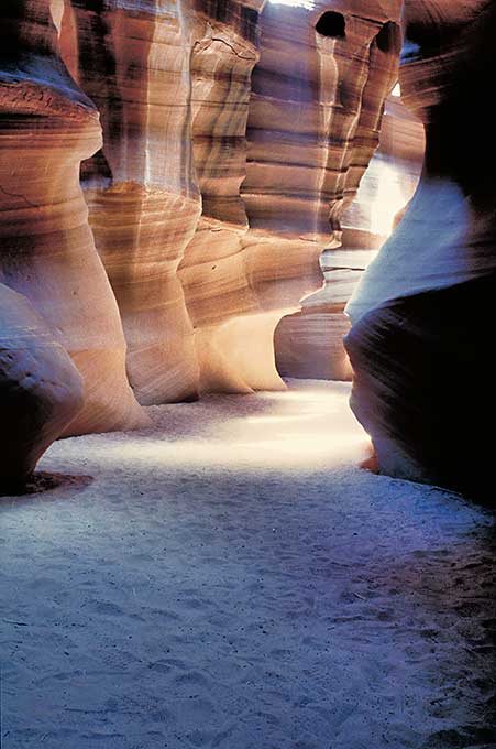 Some brown-beige colored rock formations with surfaces finely marked by erosion caused by water flowing through them.